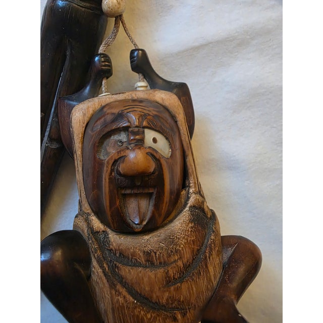 A striking and highly expressive hand-carved wooden sculpture featuring a whimsical figure with exaggerated facial...