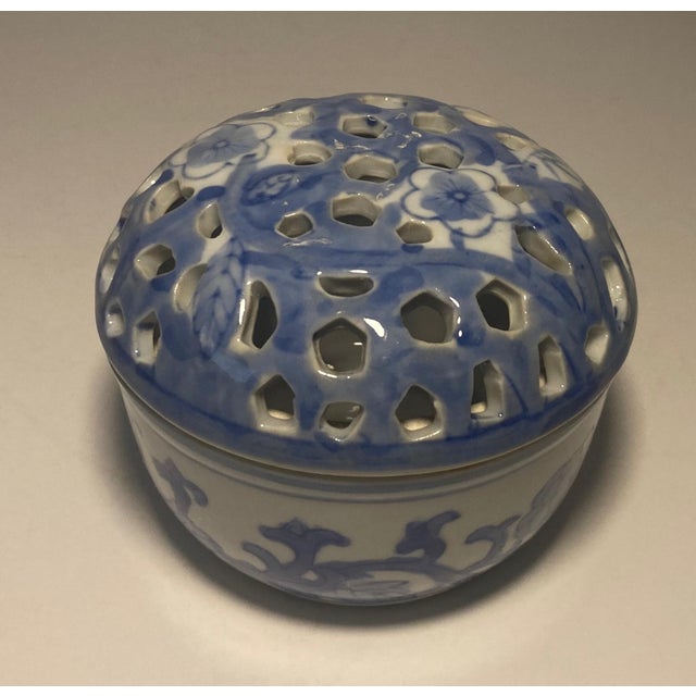 Two sweet lidded Chinoiserie hand painted porcelain boxes. The round box is painted with flora and topped with a pierced...