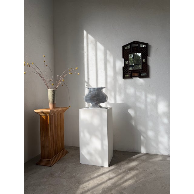 Cast aluminum vase with a generous shape and curved lines, representing a classic vase form, but with a flatter shape that...