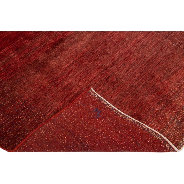 Beautiful modern Gabbeh-style hand-woven wool rug with a red color field. This Persian rug has a gorgeously minimalist...