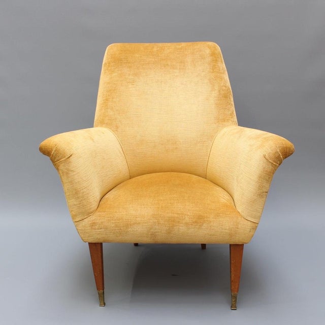 A stylish and inviting pair of italian mid-century modern armchairs, reupholstered in a rich golden-yellow velvet that...