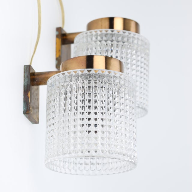 Elegant pair of sconces by Carl Fagerlund for Orrefors made in Sweden around 1960, diamond cut cast glass mounted on brass...