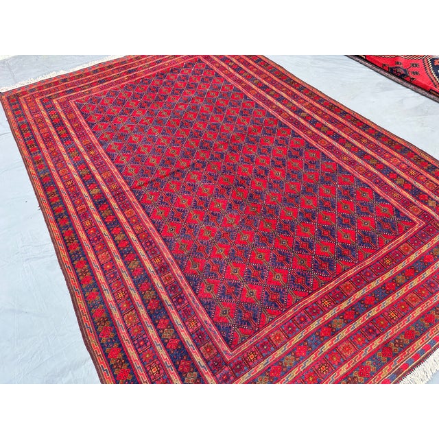 This vivid Andkhoy rug features a fine diamond trellis alternating between rich crimson and deep indigo compartments,...