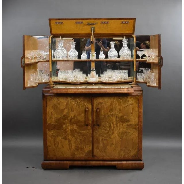 An exceptional Art Deco cocktail cabinet, crafted in burr walnut with a striking book-matched grain and gently rounded...