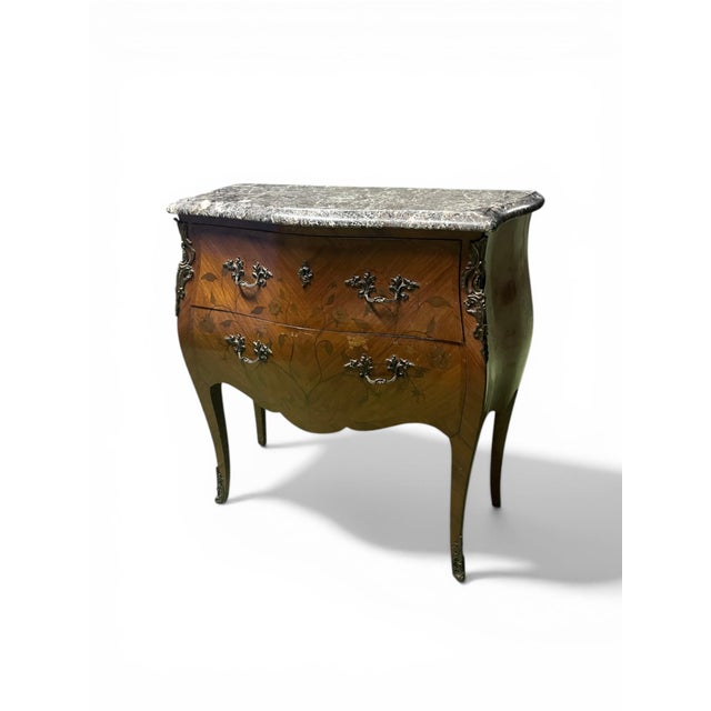 An elegant louis xv style bombé commode, stamped, with richly decorated marquetry and chased bronze mounts. its front...