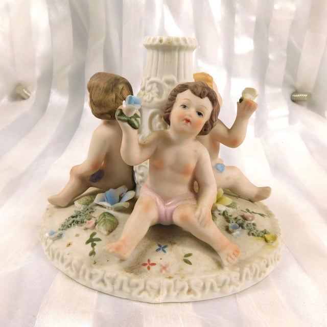 This is a Dresden Carl Thieme candle holder with three babies holding flowers. At least, it looks like a candle holder...