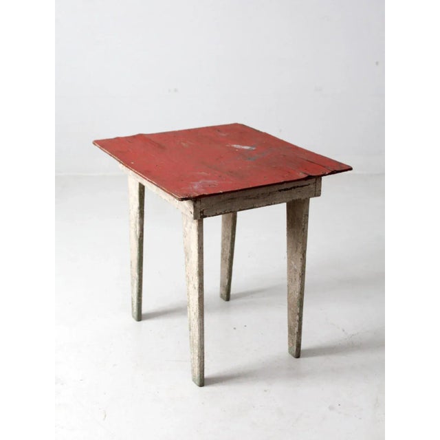 This is a rustic vintage side table. The charmingly weathered wooden farmhouse table features a painted red top with white...