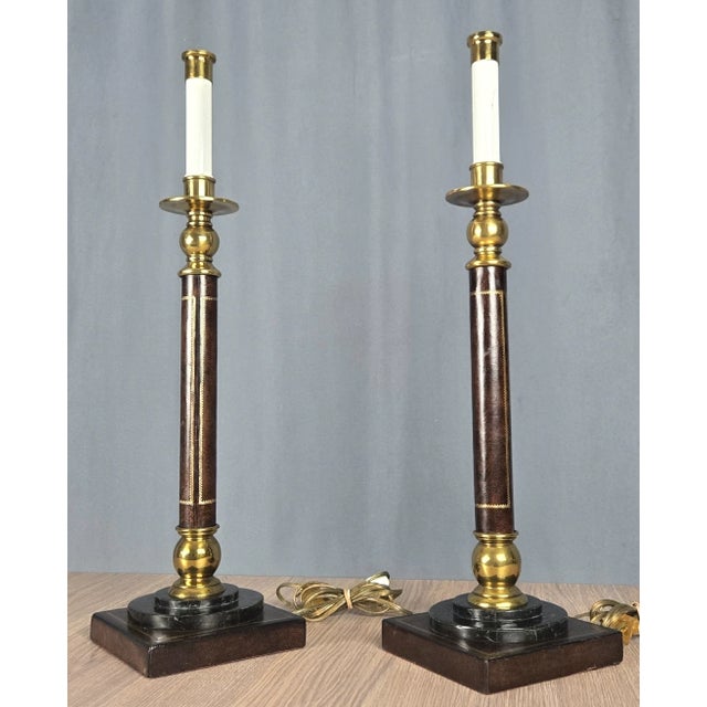 Pair of handsome candlestick motif lamps. Polished brass, leather wrapped uprights and bases with marble trim. Retain made...