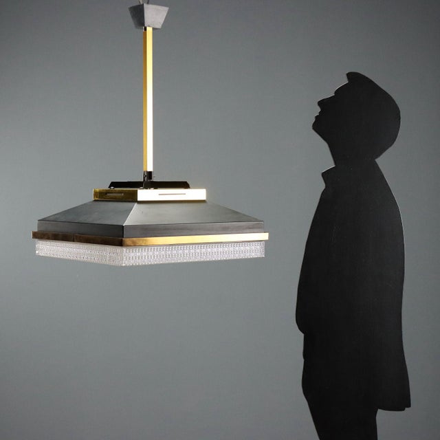 1960s ceiling lamp featuring an enameled metal structure with elegant brass-plated aluminum profiles. The design is...