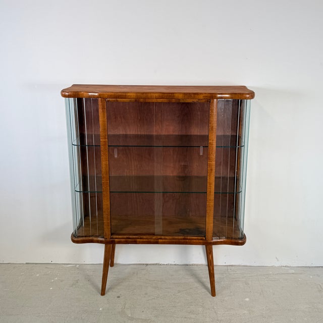This distinctive 1950s display cabinet, originating from Poland, immediately catches the eye with its elegant curved Art...