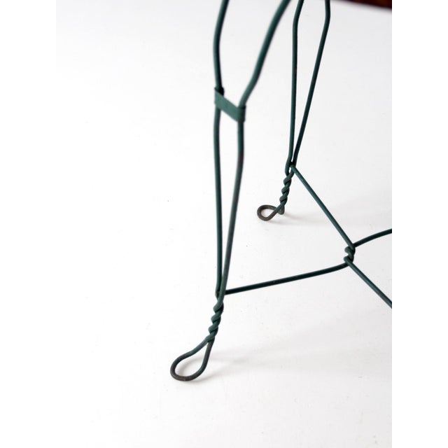 This vintage mid-century bistro table pairs a warm round wood top with a wrought iron base in a deep green tone. The...