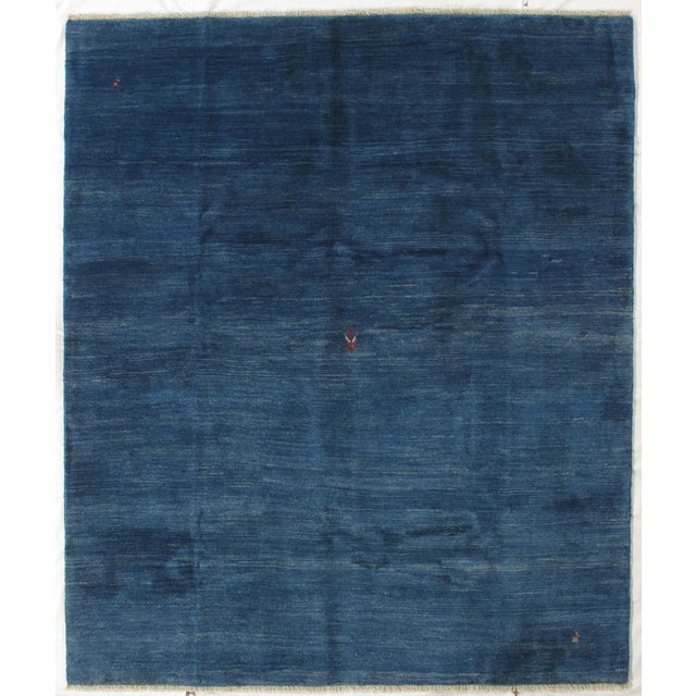 Vintage hand-knotted Persian Gabbeh rug featuring a deep blue field with subtle tonal variation and scattered small tribal...