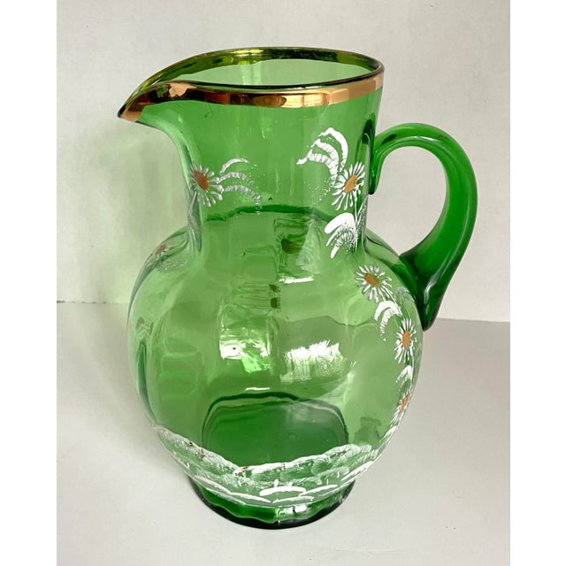 Here is a glowing pitcher that is handblown from bright, green glass and has been adorned with original painted flowers...