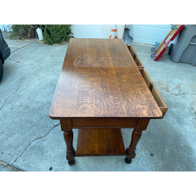 This antique Arts and Crafts oak library desk writing table with a shelf in a mission style is a vintage console table...