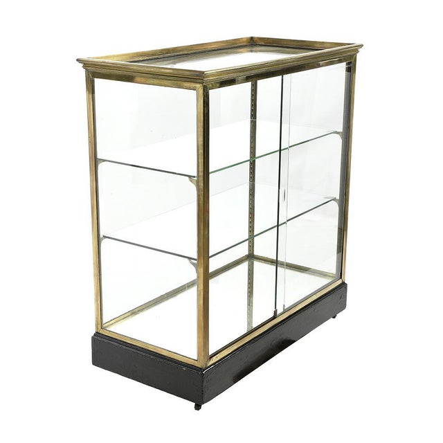 Beautiful brass display case with wooden base. Antique brass and wood storage cabinet. Has 2 glass shelves. The cabinet is...