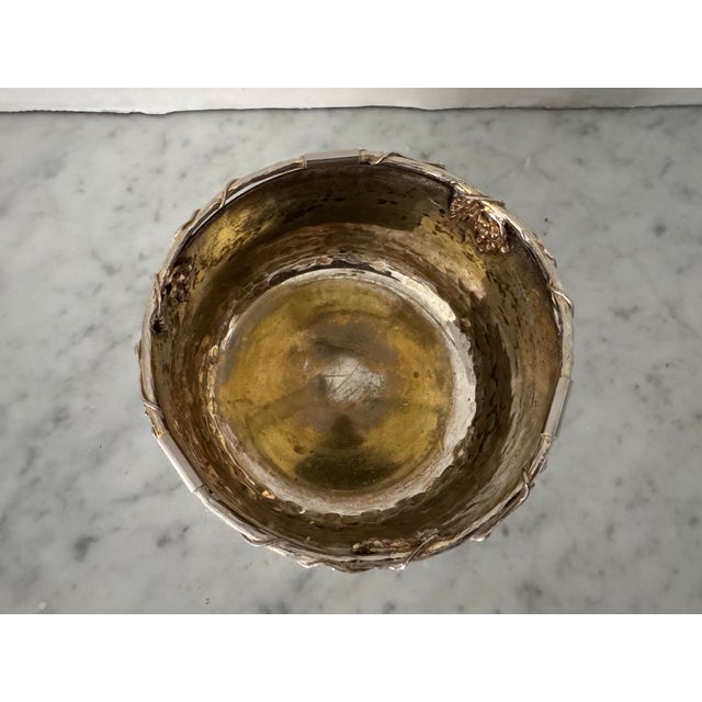 An antique silver over copper wine coaster decorated with grape vines.