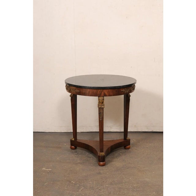 A French Neoclassical round-shaped occasional table with black marble top and revival accents, from the early 19th...