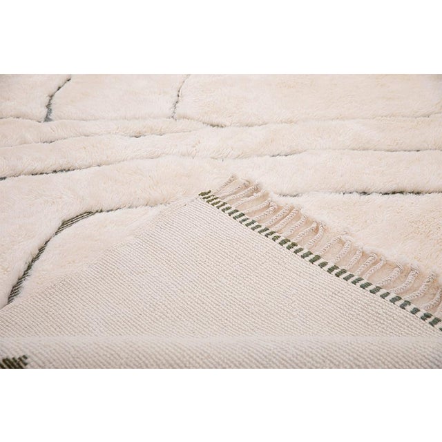 Branches in motion, sketched across an ivory canvas. This hand-knotted Moroccan wool rug features delicate, meandering...