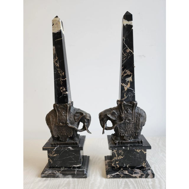 Intricate and detailed sculptural Bernini style bronze elephants supporting a Portero marble obelisk on a matching marble...