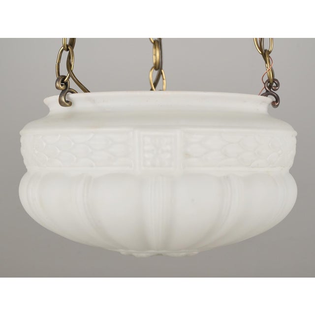 Vintage pendant light made of a white ornate fluted bowl glass shade, brass finished canopy, and steel chain. This...
