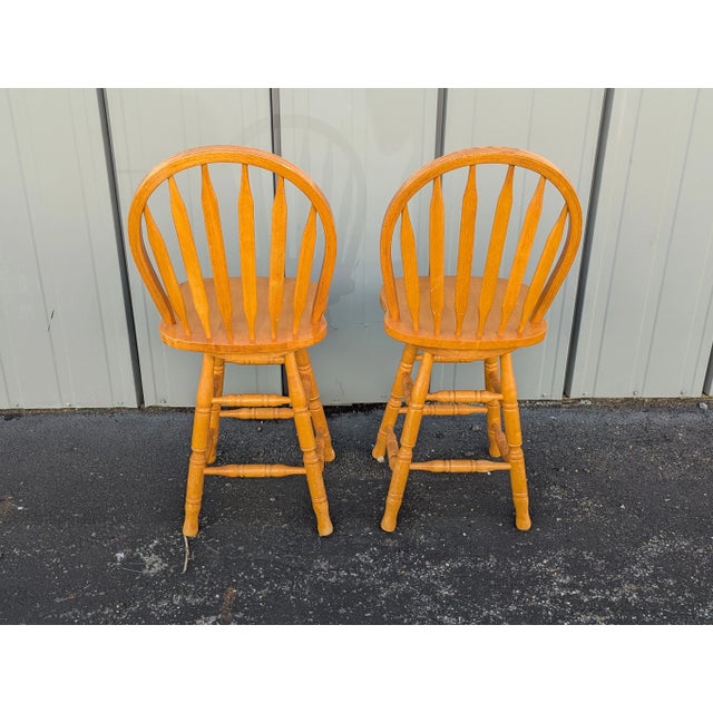 These are vintage bar or counter chairs from the 1970s or 1980s, constructed from solid oak wood. They feature a classic...