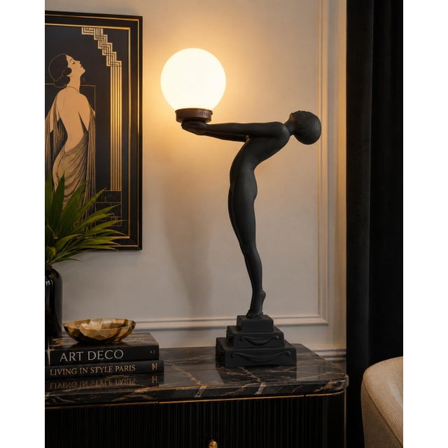 A dramatic late 20th-century Art Deco Revival figural table lamp featuring a stylized nude female figure gracefully posing...