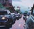 In "Lunch Rush," a bustling city street is captured during a moment of pause, as cars line up in a traffic jam beneath a...
