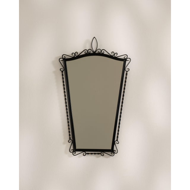 A tall wrought iron mirror with a softly tapered silhouette, adding subtle sculptural interest. The simple metal frame...