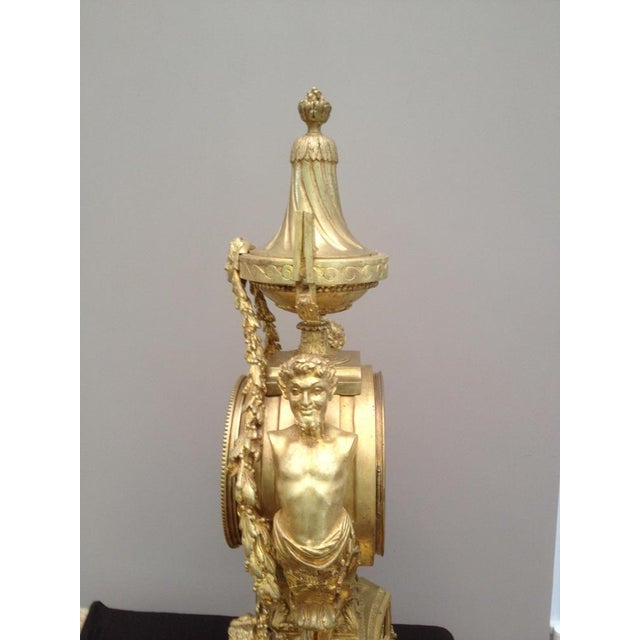 This is a stunning gilt bronze French clock that has depicting fawns, garlands, mythical faces, white porcelain face with...