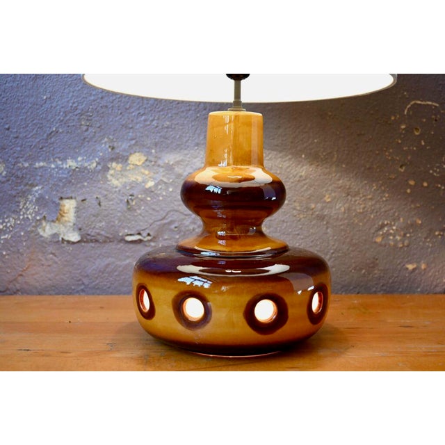 This table lamp has a colored and openwork ceramic base. This retro light accessory will add to the ambiance of the room....