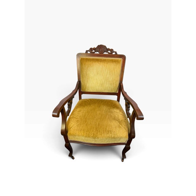 Striking antique Victorian armchair on wood-wheel casters featuring a richly finished mahogany-toned wood frame, dramatic...