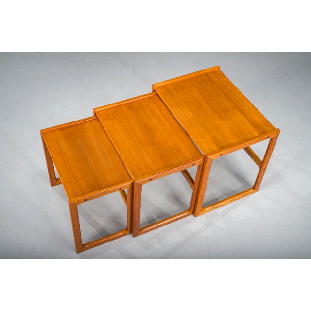 This elegant set of three nesting teak tables from the 1960s embodies the timeless appeal of Scandinavian design. Crafted...