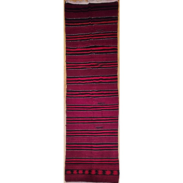 This vibrant vintage Turkish kilim runner, handwoven in Anatolia during the mid-20th century, showcases the timeless...