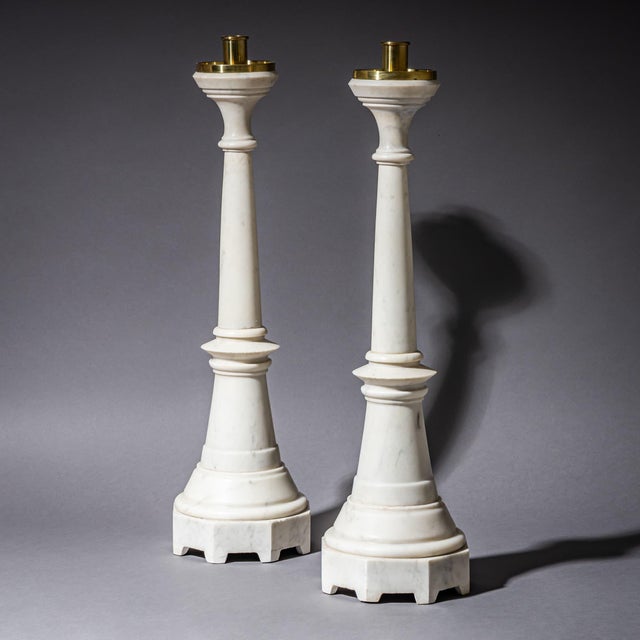 Pair of large altar candlesticks crafted from white marble with grey veining and fitted with brass candle sockets. The...