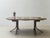 The round dining table by Dietiker is made of wood and features a striking, curved base. The warm, medium-brown color...