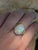 This striking ring showcases a 7.33-carat untreated Ethiopian opal, measuring 17.03 x 12.5mm, known for its vivid play-of-...