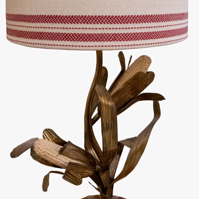 A lamp in gilded brass, with handcrafted leaves and cream-colored corn cobs. Inspired by the Hollywood Regency style of...
