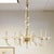 A champagne colored Murano glass chandelier featuring 6 scroll form arms, each ending in a glass bobeche and candle style...