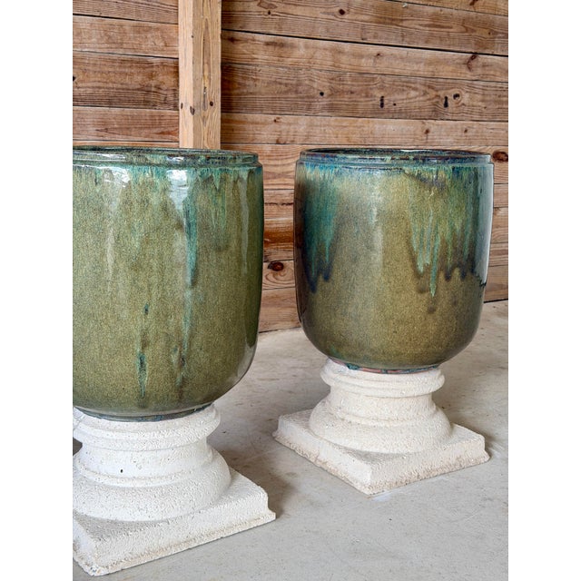 A striking pair of large-scale glazed ceramic garden planters presented on separate classical-style cast stone pedestal...