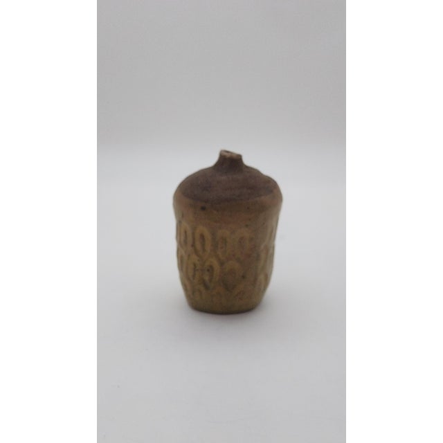 Handcrafted stoneware bud vase with an organic sculptural silhouette and richly textured surface. The vessel features a...