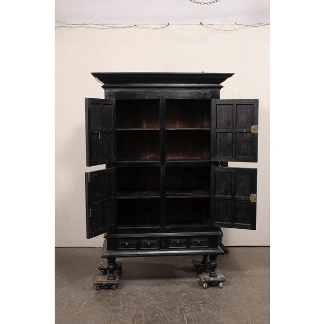 A British Colonial ebonized wood tall cabinet from the early 20th century. This antique British Colonial cabinet from...