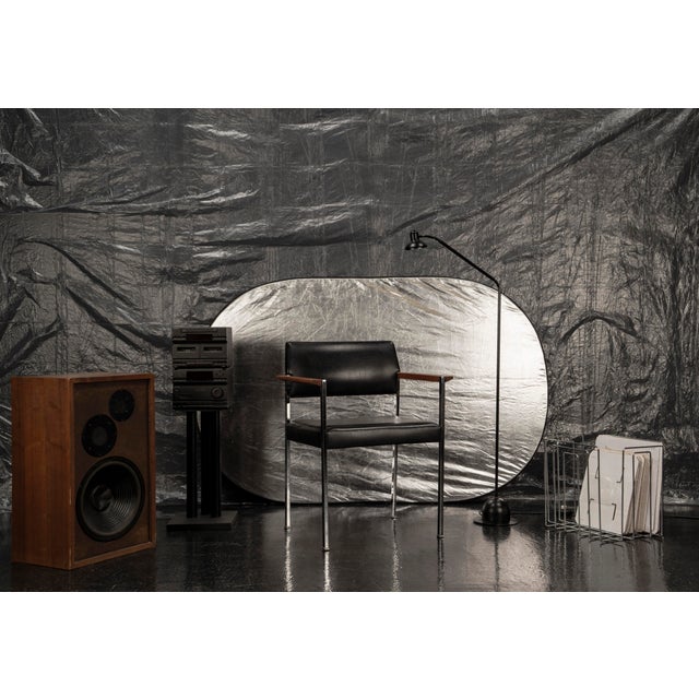 This black armchair with armrests dates from the 1960s and impresses with its timeless design. Made of chrome plated steel...