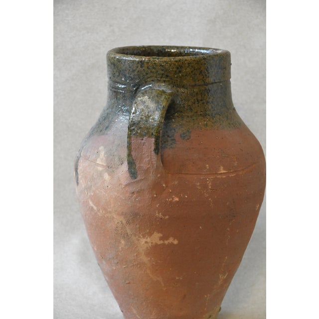 This antique Mediterranean olive jar has a rich, weathered green glaze, rounded form, and two sturdy side handles that...