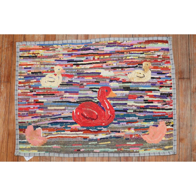 A handmade decorative American hooked rug from the middle of the 20th century with a few jolly ducks floating on a...