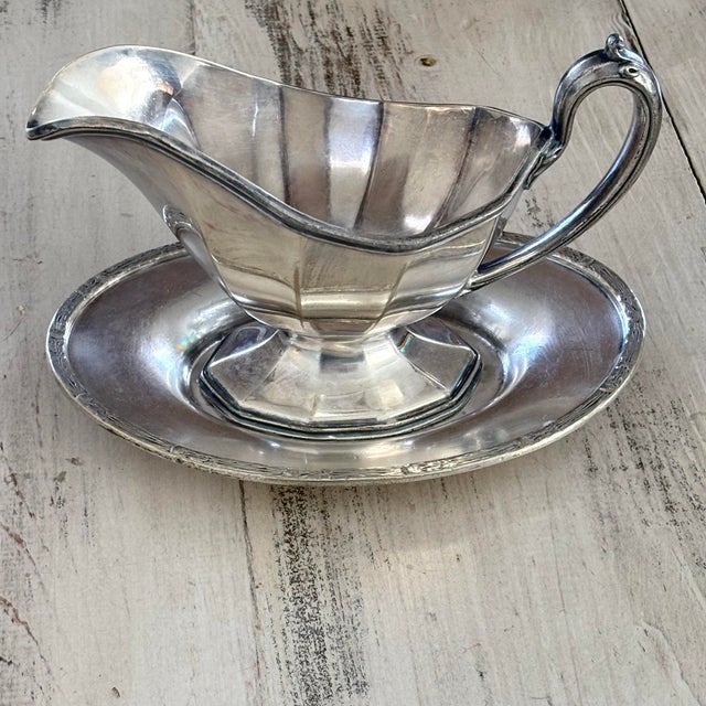 "An elegant vintage silver-plated gravy boat featuring a paneled, multi-faceted body by the renowned silversmiths Reed &...