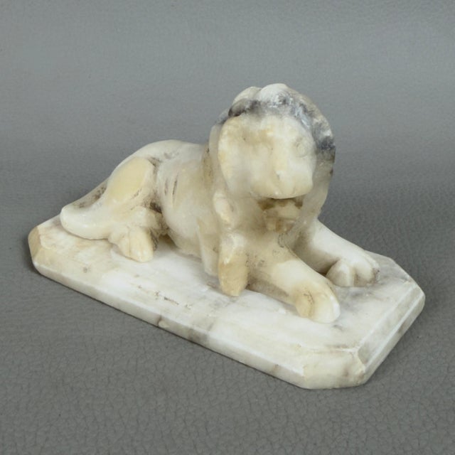 A fine freestanding white marble sculpture depicting a crouching lion, attributed to early 20th-century craftsmanship....