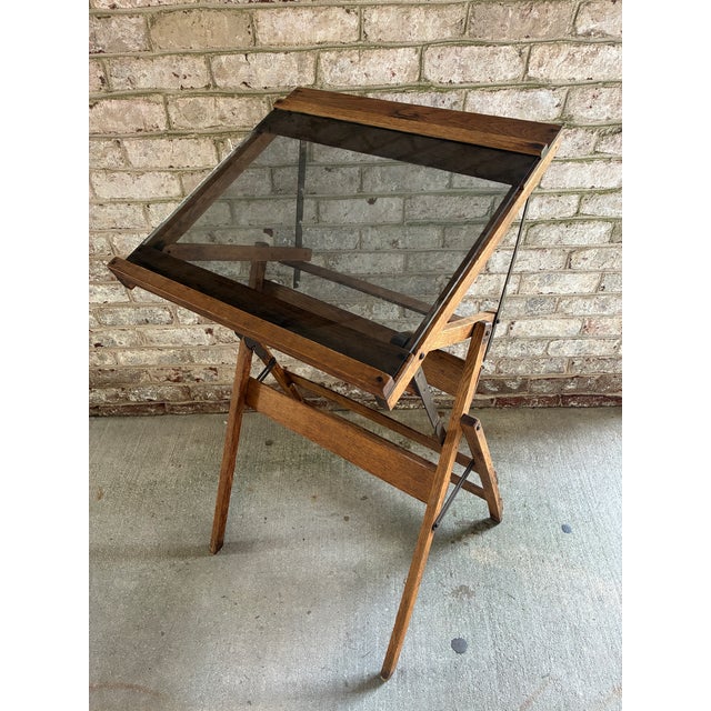 Vintage wooden adjustable writing table, featuring a tilting smoked glass top and a folding oak frame. This piece is fully...
