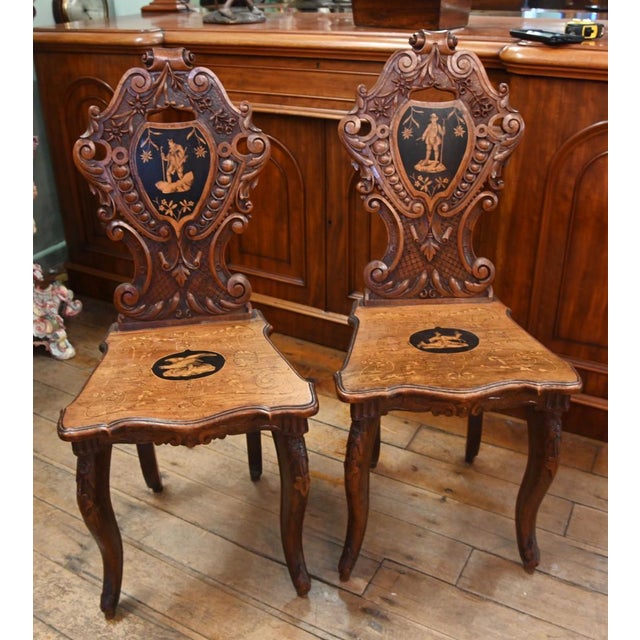 Pair of Black Forest carved walnut hall chairs Features inlaid panels showing medieval hikers, perhaps on some pilgrimage...