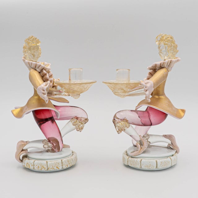 A whimsical and refined Murano-style glass figurine depicting a robed Venetian gentleman holding a scalloped glass...