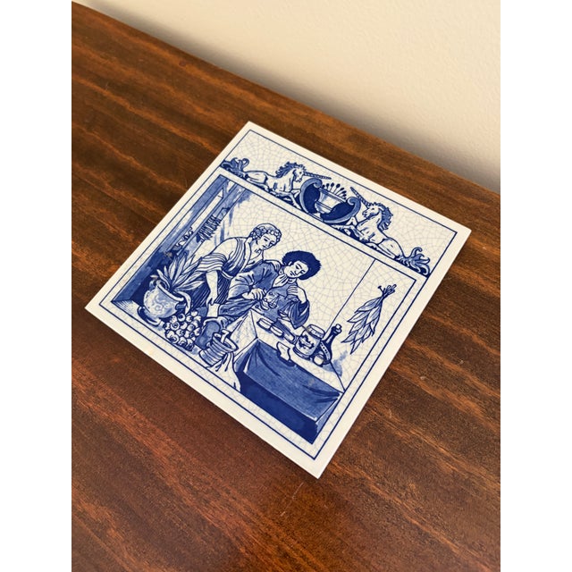 A classic Dutch Delft-style hand painted blue and white porcelain tile featuring a scene of Herbalists in rich cobalt blue...